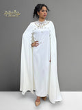 Woman wearing a white dress attached with a cape standing against a gray background. Brand 'Bellanaisa Canada' visible.