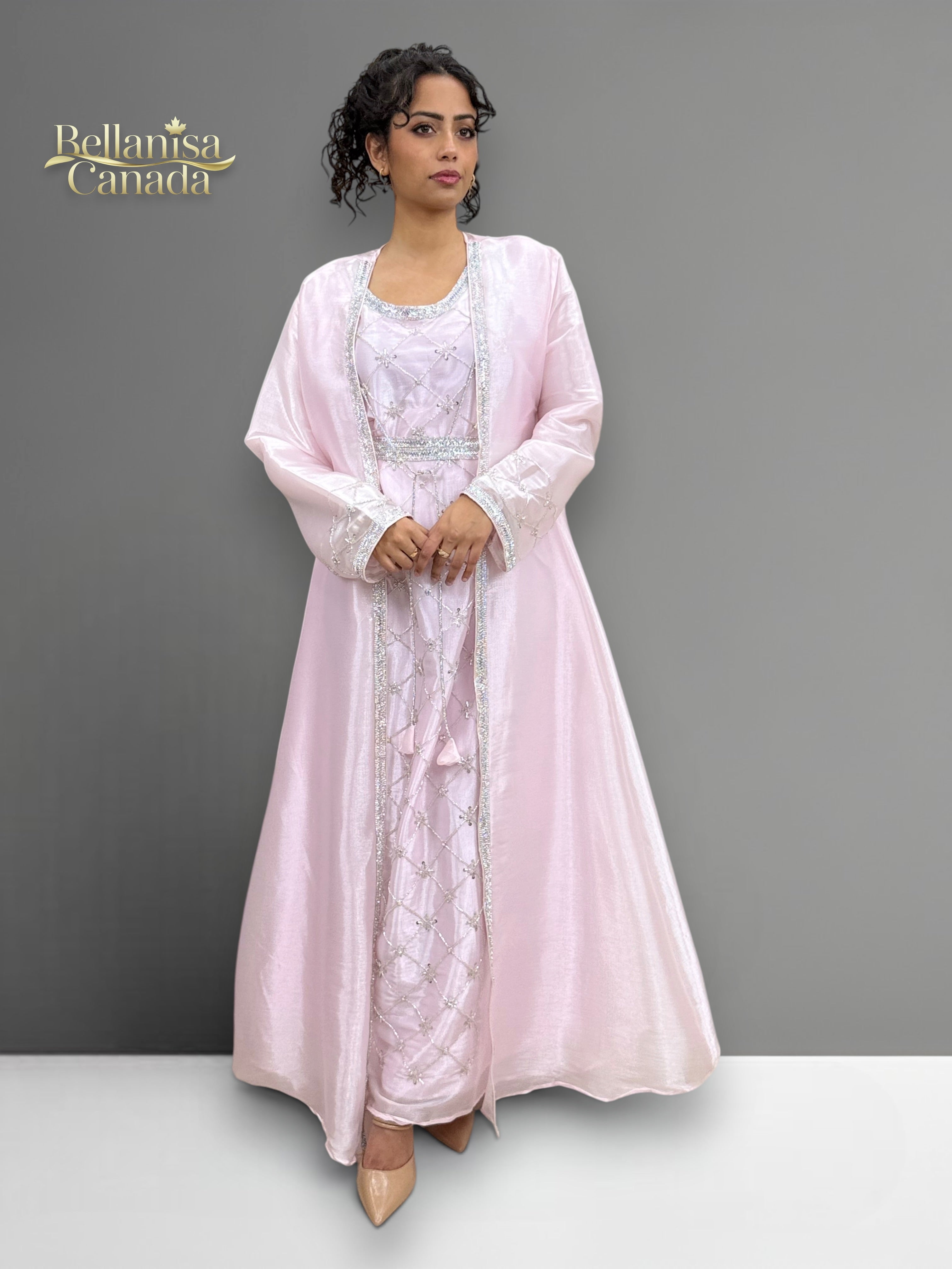 Model wearing a light pink Morrocan Kaftan with a matching jacket against a gray background.