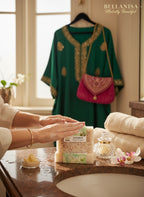 Person applying soap to hands with a green embroidered dress and pink bag in the background.